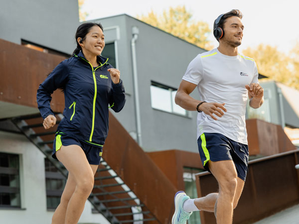 Dois participantes da corrida a correr com os seus auscultadores Philips.